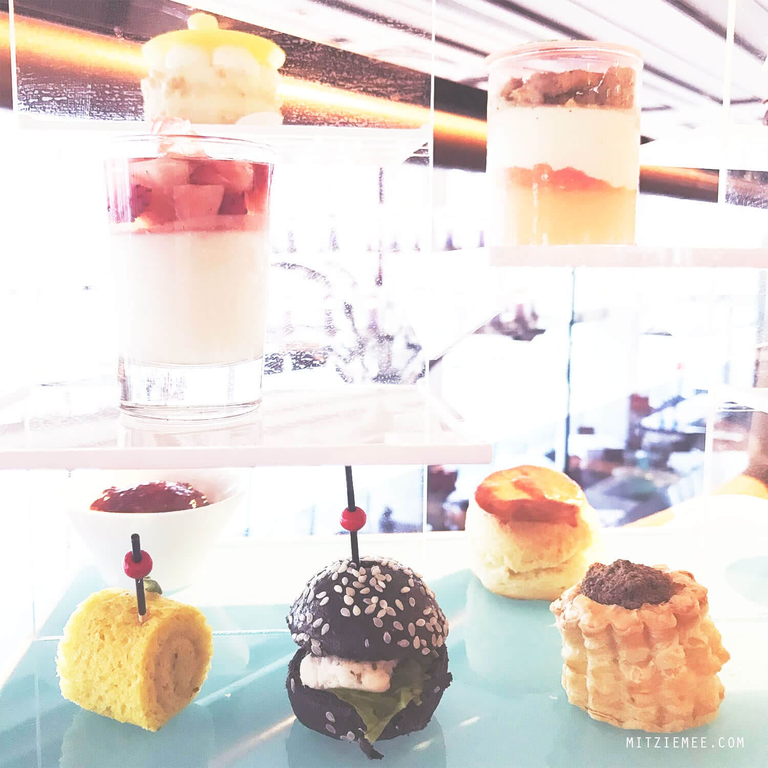  On my last day in Hong Kong it was pouring down. I had to check out from the hotel at noon, but my flight was not until the evening, and my original plan to go for a walk along the water did not seem very attractive. Instead I called The Ritz-Carlton in Hong Kong and made a reservation for the afternoon tea at Café 103. My table was far from the floor-to-ceiling windows, so even though I was on the 103rd floor, I did not have much of a view. Instead they provided me with different kinds of magazine, so I wouldn’t get bored during my afternoon tea for one. Except for the view (or the lack of it), it was a really nice afternoon tea. First, I was asked to pick the tea I wanted, and it was more difficult than it sounds, because there were so many different kinds to choose among. After consulting the waiter, who turned out to be very well-versed in teas, I finally decided on the Sakura Sakura tea, which was a green tea with cherry blossoms and a mild and flowery flavor. The Ritz-Carlton in Hong Kong are known for collaborations with chefs and different gourmet brands for the afternoon tea, and when I was there, the menu was made in collaboration with luxury candy store Sugarfina, which are particularly known for boozy gummy bears. One of the desserts I had was a champagne cream with strawberry topped with a champagne-infused gummy bear, and it was exquisite. I could have eaten a whole family of those bears:) It was a nice way to spend the afternoon but next time I go, I will try to get a table with a better view. I did a little online research, and it seems like The Lounge & Bar, which is on the 102nd floor and also serves afternoon tea, has more window tables available, so maybe they are a better choice. Otherwise, there is always Ozone, which is the beautiful bar on the 118th floor at the Ritz-Carlton. 