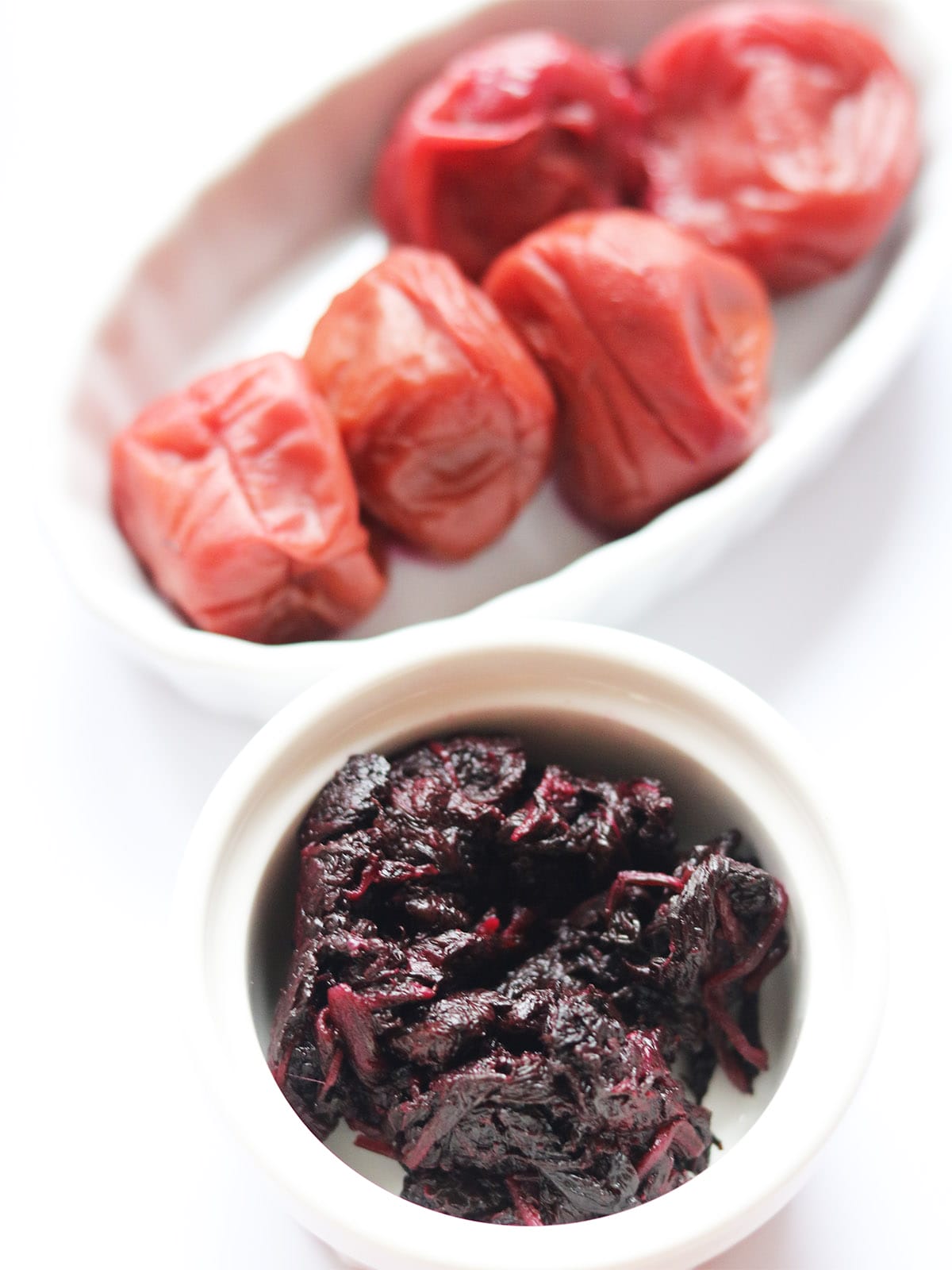 A common variation of umeboshi is pickled with red shiso leaves (aka shiso), which gives them their signature deep red color and an added layer of flavor. Shiso (紫蘇) is a Japanese herb from the mint family, with a taste that falls somewhere between basil, mint, and anise, with a slightly earthy, almost cinnamon-like note. The red variety is often used to dye and flavor umeboshi, balancing out the saltiness with a Umeboshi